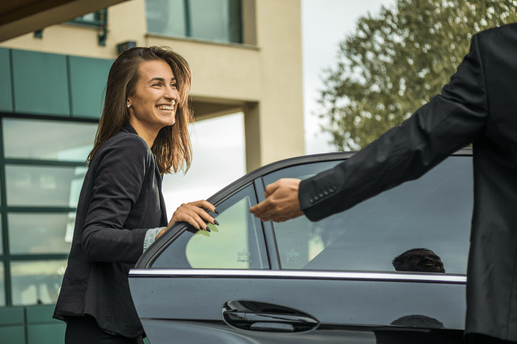 Woman smiling and getting into a taxi booked by Venue Butler